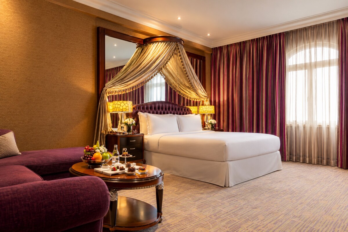 A hotel room with a large bed, a sitting area with a table, and a large mirror.