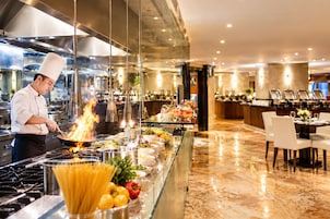 Un chef cocina entre llamas en una cocina moderna con una zona de buffet al fondo.