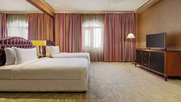 Una habitación de hotel con una cama grande, televisión y un armario.