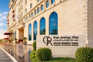 Un edificio imponente con ventanas de arco y un cartel que indica que es el Grand Regency Doha.