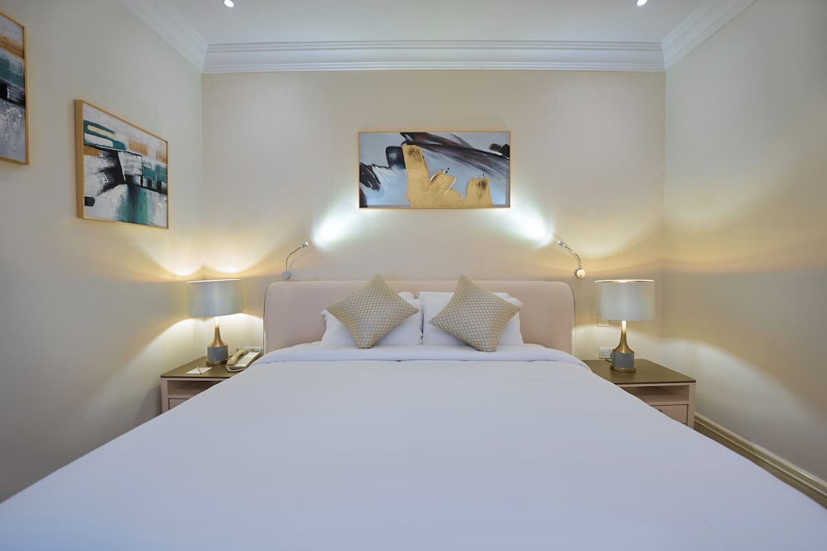 Una habitación de hotel con una cama grande, dos mesitas de noche con lámparas y obras de arte en las paredes.