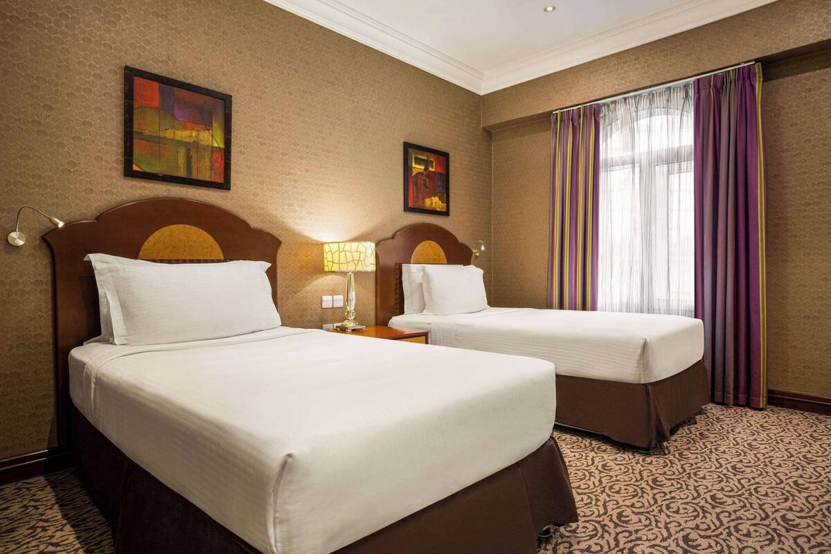 Una habitación de hotel con dos camas, una alfombra estampada y obras de arte en las paredes.