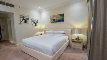 A hotel room with a large bed, two bedside tables with lamps, and artwork on the walls.