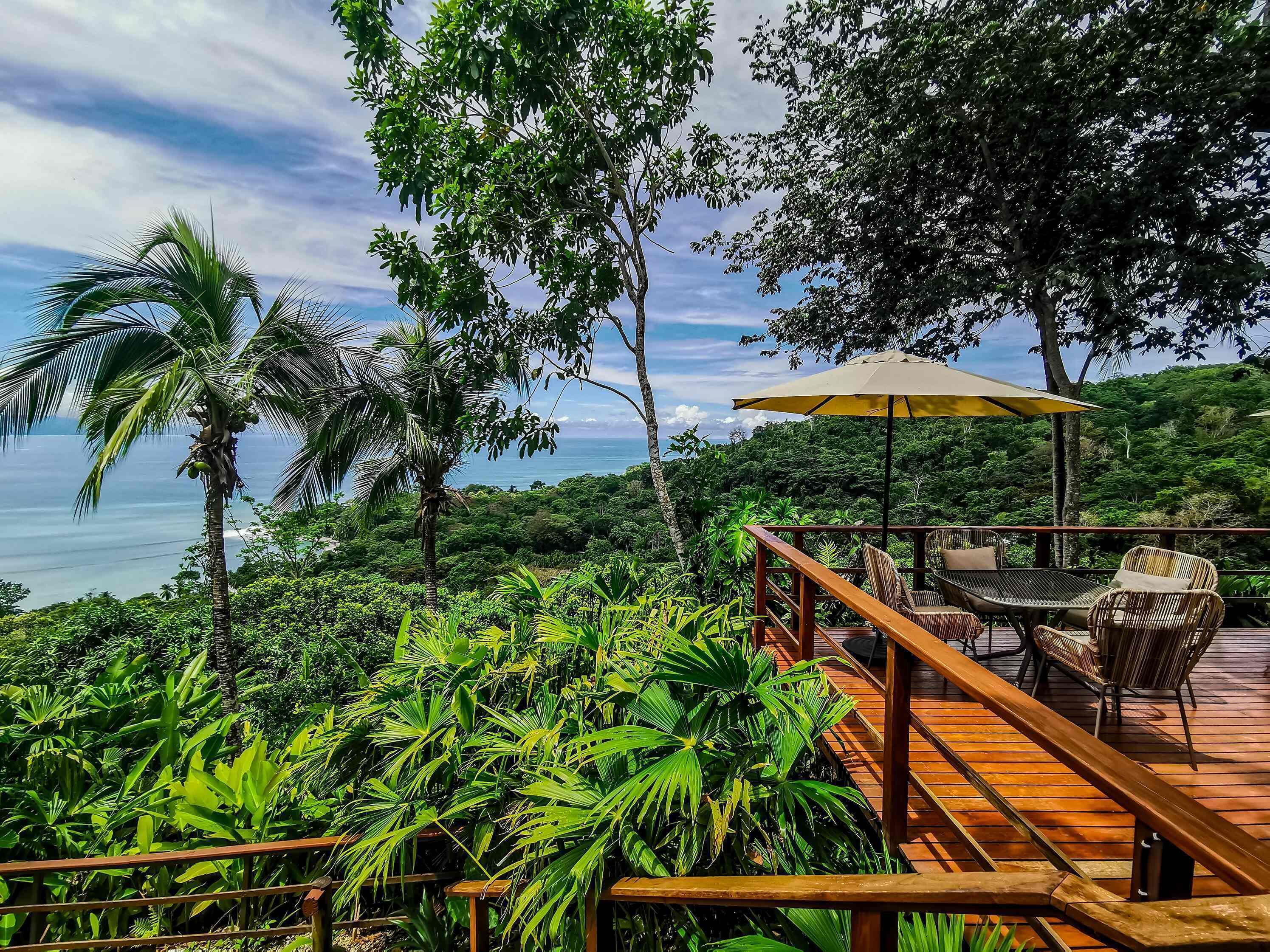 Una terraza de madera con mobiliario exterior y vistas al océano.