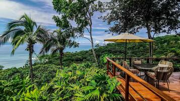 Una terraza de madera con mobiliario exterior y vistas al océano.