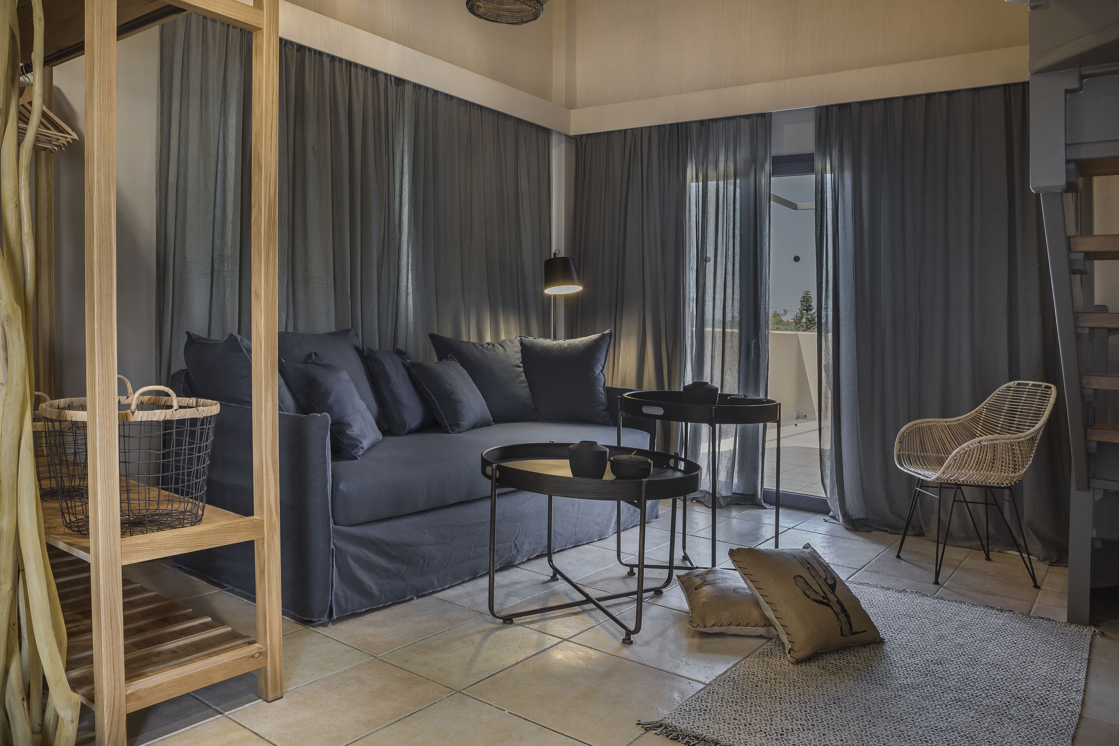 A modern living room with a dark blue sofa, a round black coffee table, and a wicker chair.
