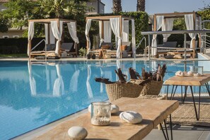 A poolside area with a clear pool, lounge chairs, and a canopy structure.