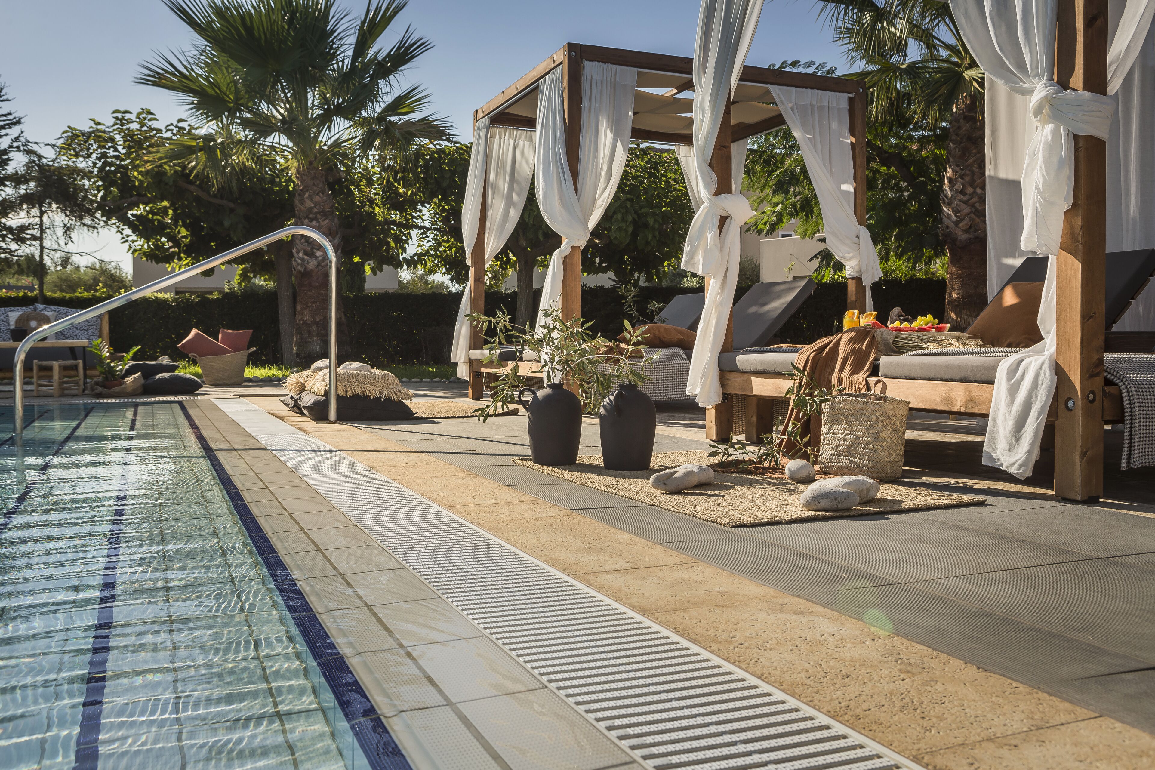 A poolside area with a canopy, lounge chairs, and a small table with fruit.