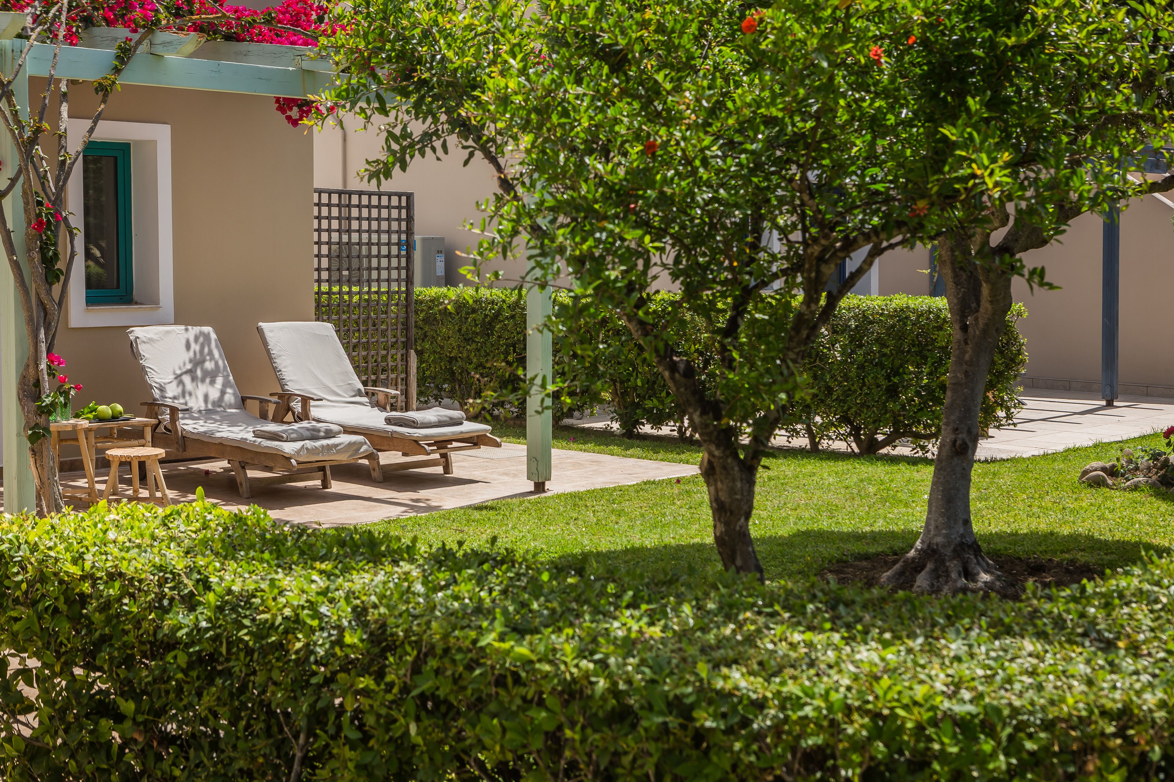 Un espace jardin agrémenté d’un arbre, d’une petite table et de deux fauteuils de relaxation.