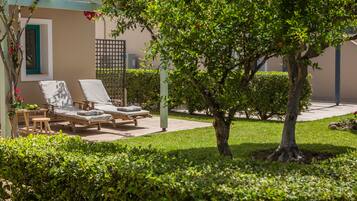 Un espace jardin agrémenté d’un arbre, d’une petite table et de deux fauteuils de relaxation.