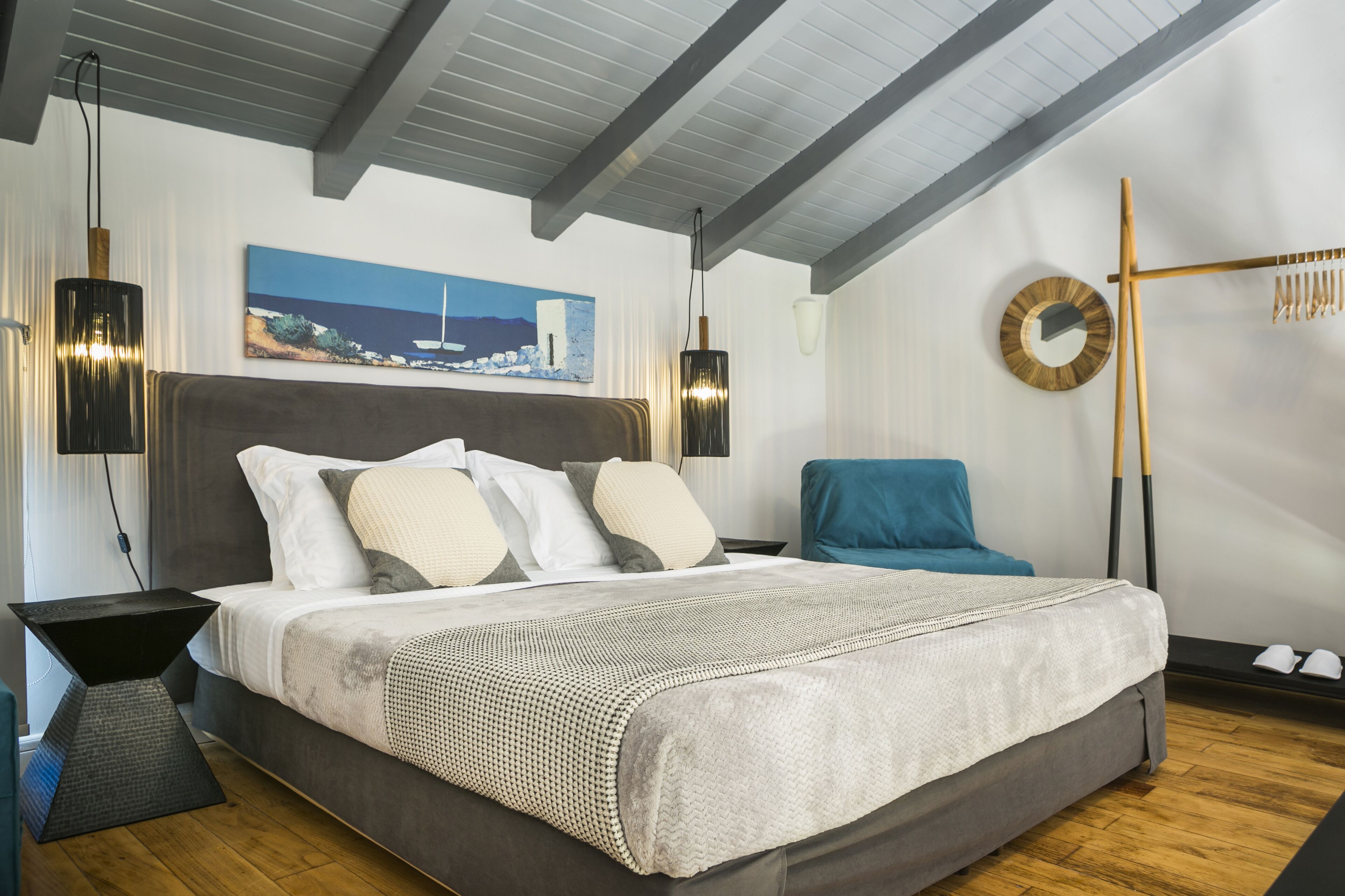 Une chambre à coucher moderne avec un grand lit, un tableau au mur et un plancher en bois.