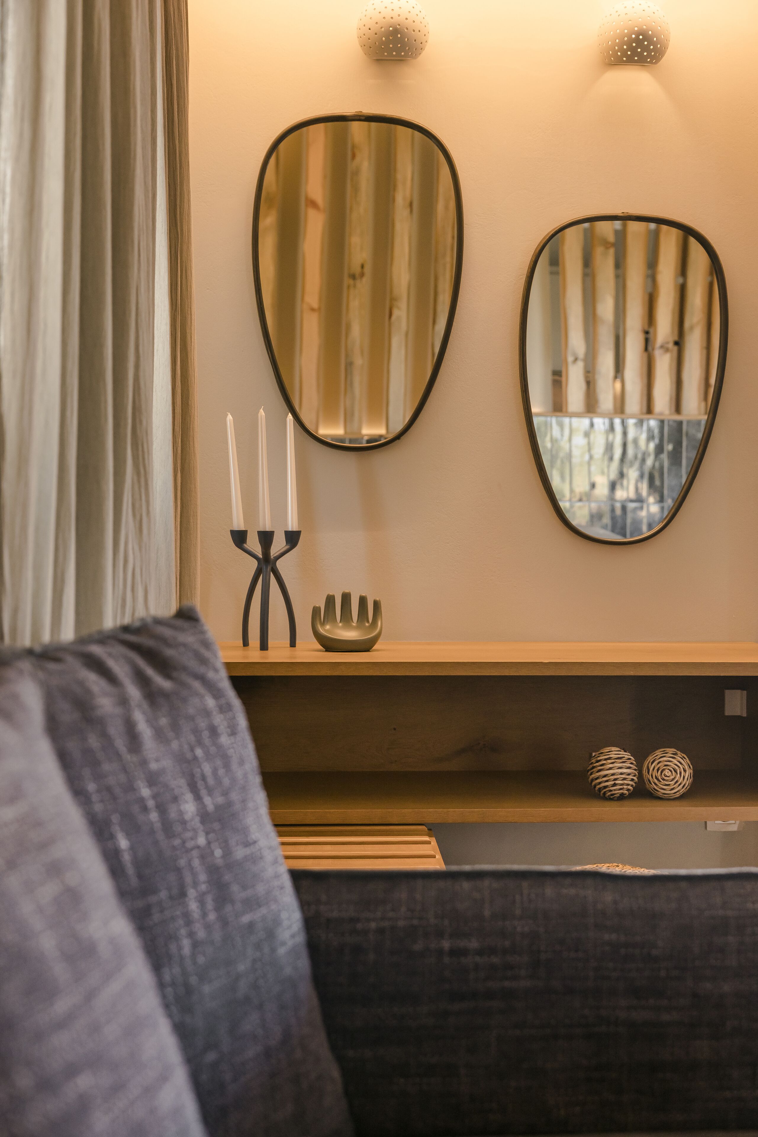 Una sala de estar moderna con un sofá, un espejo de pared, un candelabro y elementos decorativos.