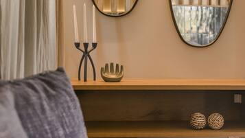 Una sala de estar moderna con un sofá, un espejo de pared, un candelabro y elementos decorativos.