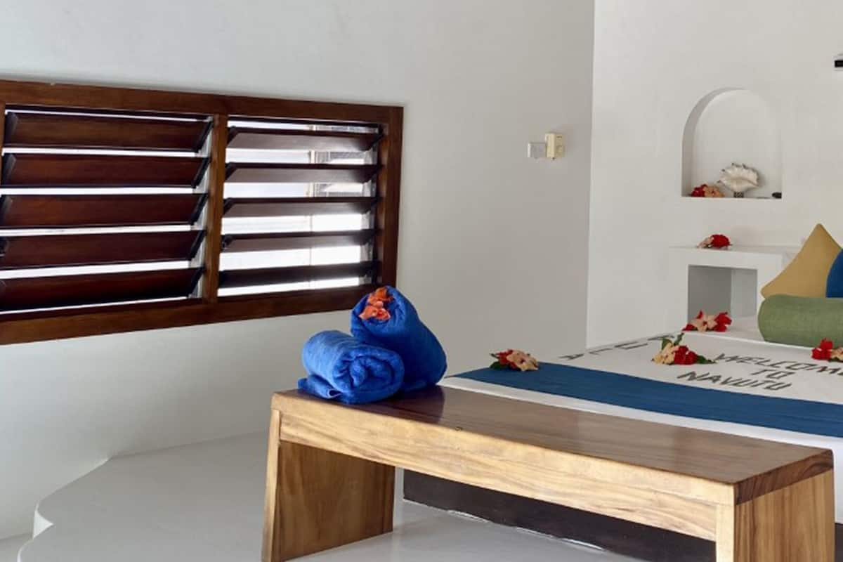 A bedroom with a bed, a wooden bench, and decorative items on the wall.