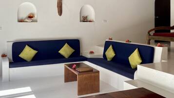 Un salon moderne avec un canapé d’angle bleu, une table basse en bois et un banc en bois agrémenté de coussins.