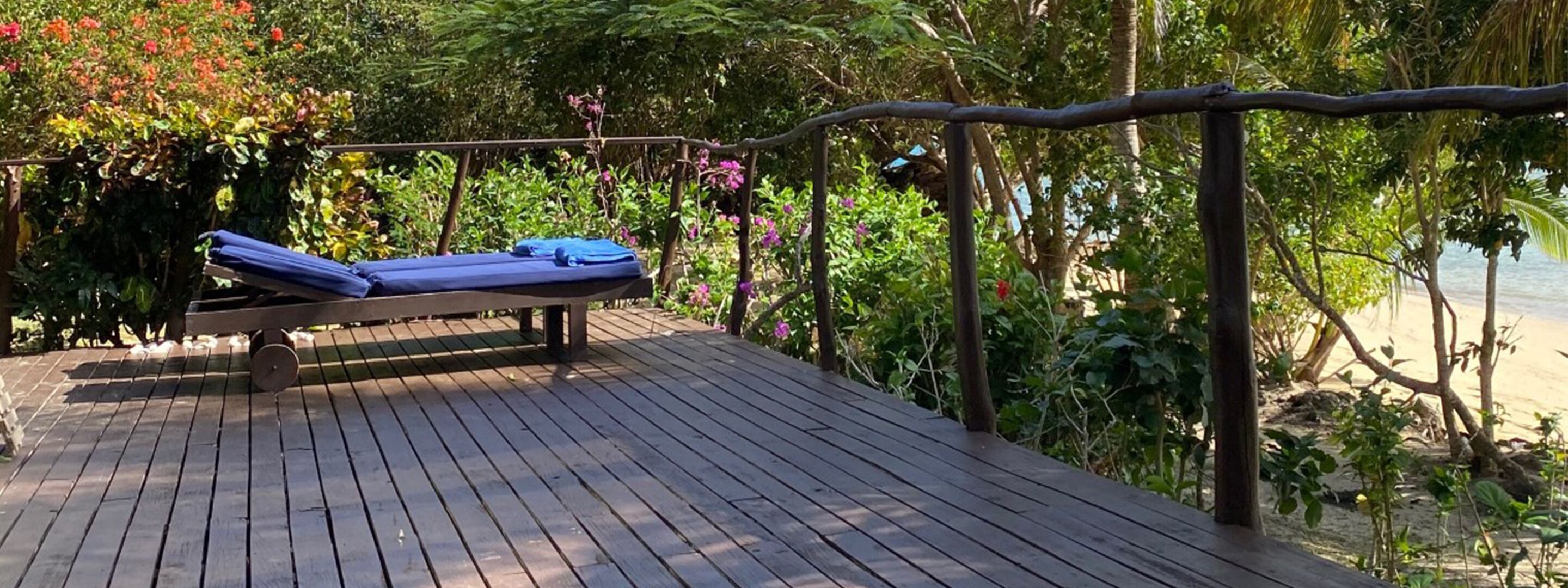 A wooden deck with a lounge chair and a pergola.
