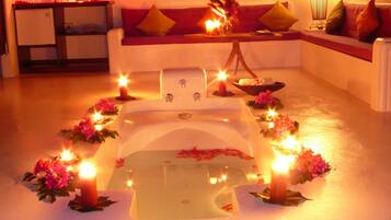 Relax in a serene space with a central bathtub, sofa, and elegant arrangements of flowers and candles.