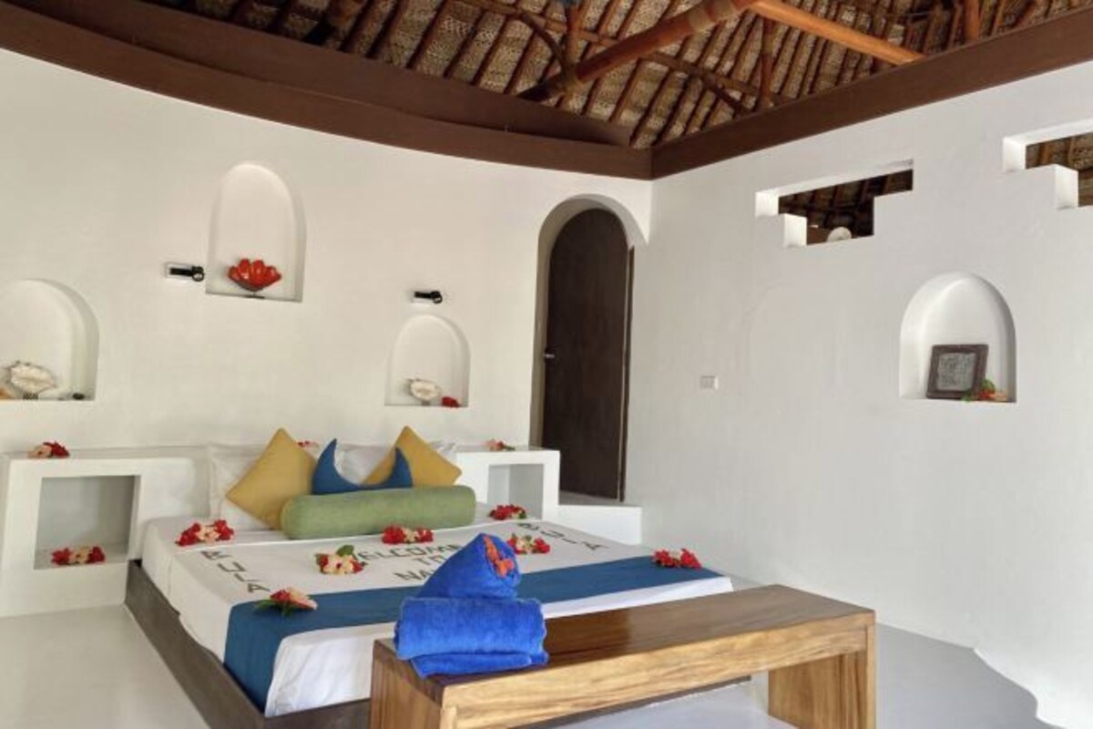 A bedroom with a bed, a wooden table, and a ceiling with exposed beams.