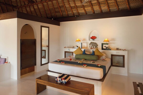 A bedroom with a bed, bedside tables, a mirror, and a wooden coffee table.