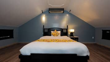 Un dormitorio con una cama grande, una mesita de noche, un aire acondicionado de pared y una luz en el techo.