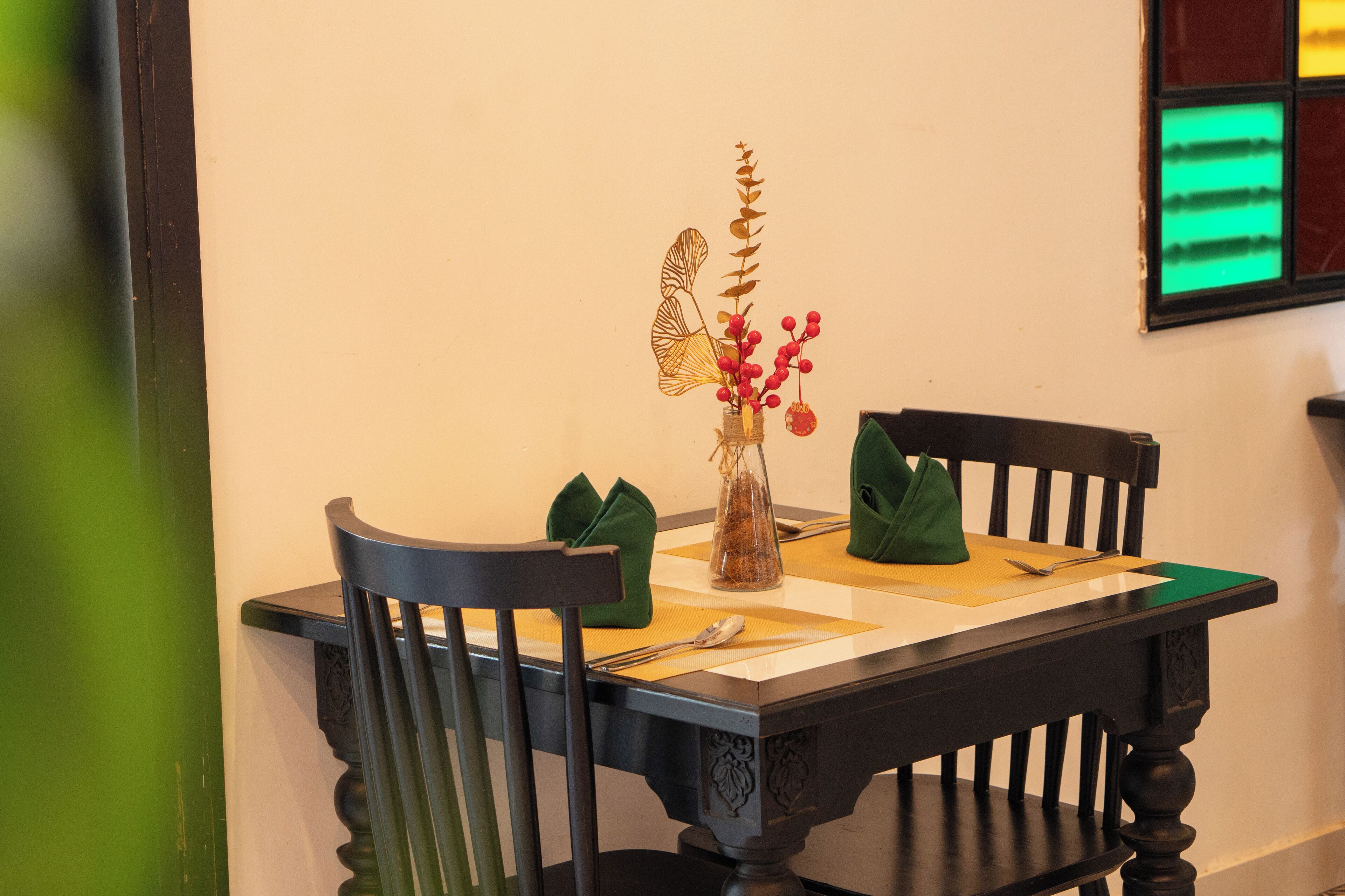 A dining table with chairs, a vase with red berries, and a decorative item resembling a butterfly.