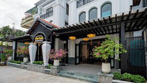 A boutique hotel entrance with a covered patio, potted plants, and a sign. - Welcome Old Town Hotel (Da Nang)