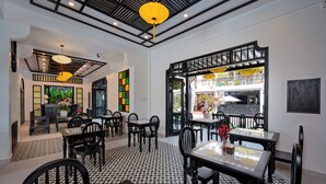 A restaurant interior with black and white patterned flooring, black and white furniture, and yellow hanging lamps. - Welcome Old Town Hotel (Da Nang)