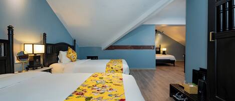 A hotel room with two beds, a wooden floor, a shoe rack, and a staircase leading to another room.