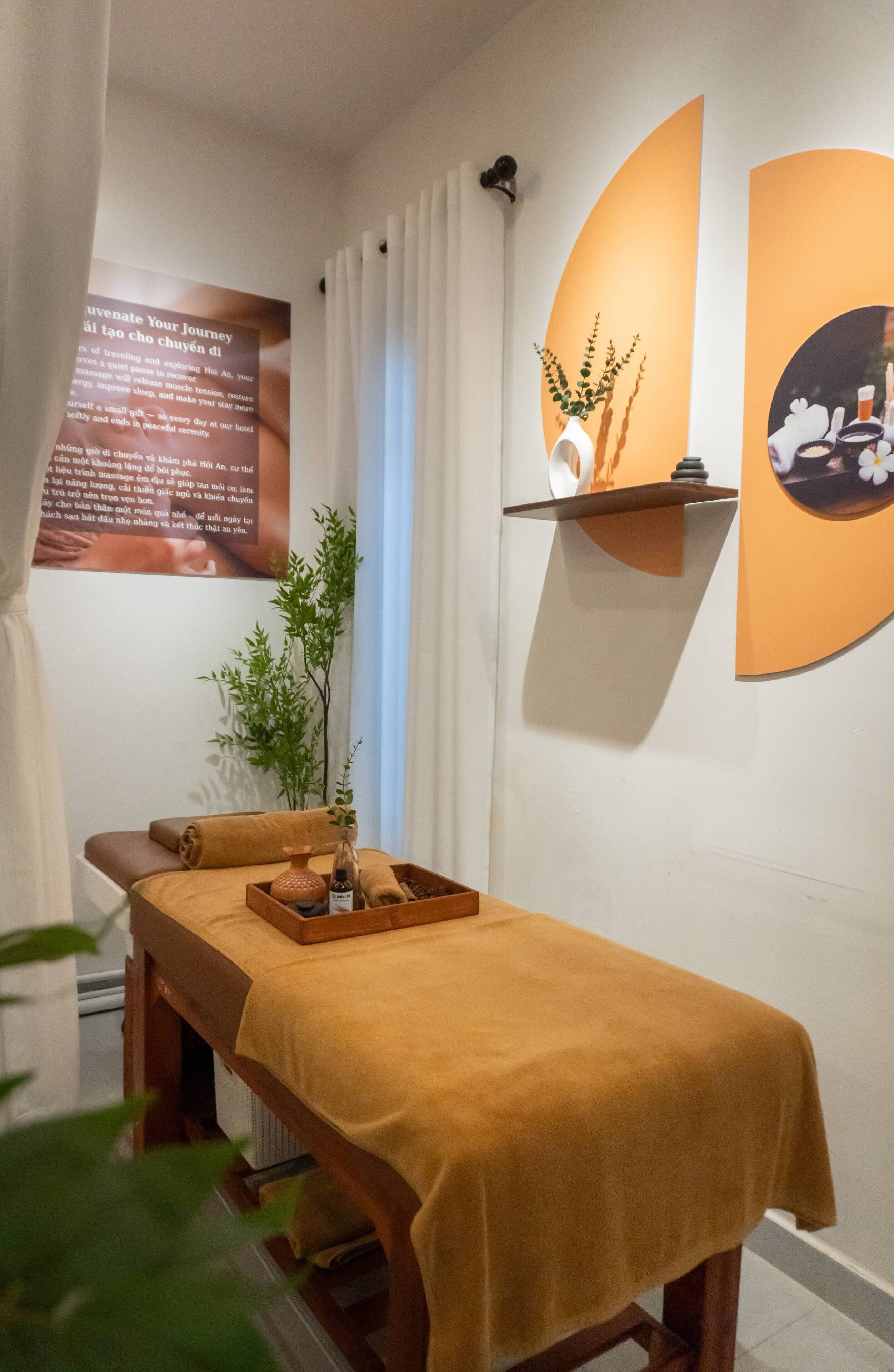 A massage table with a towel, a small plant, and a tray with bottles.