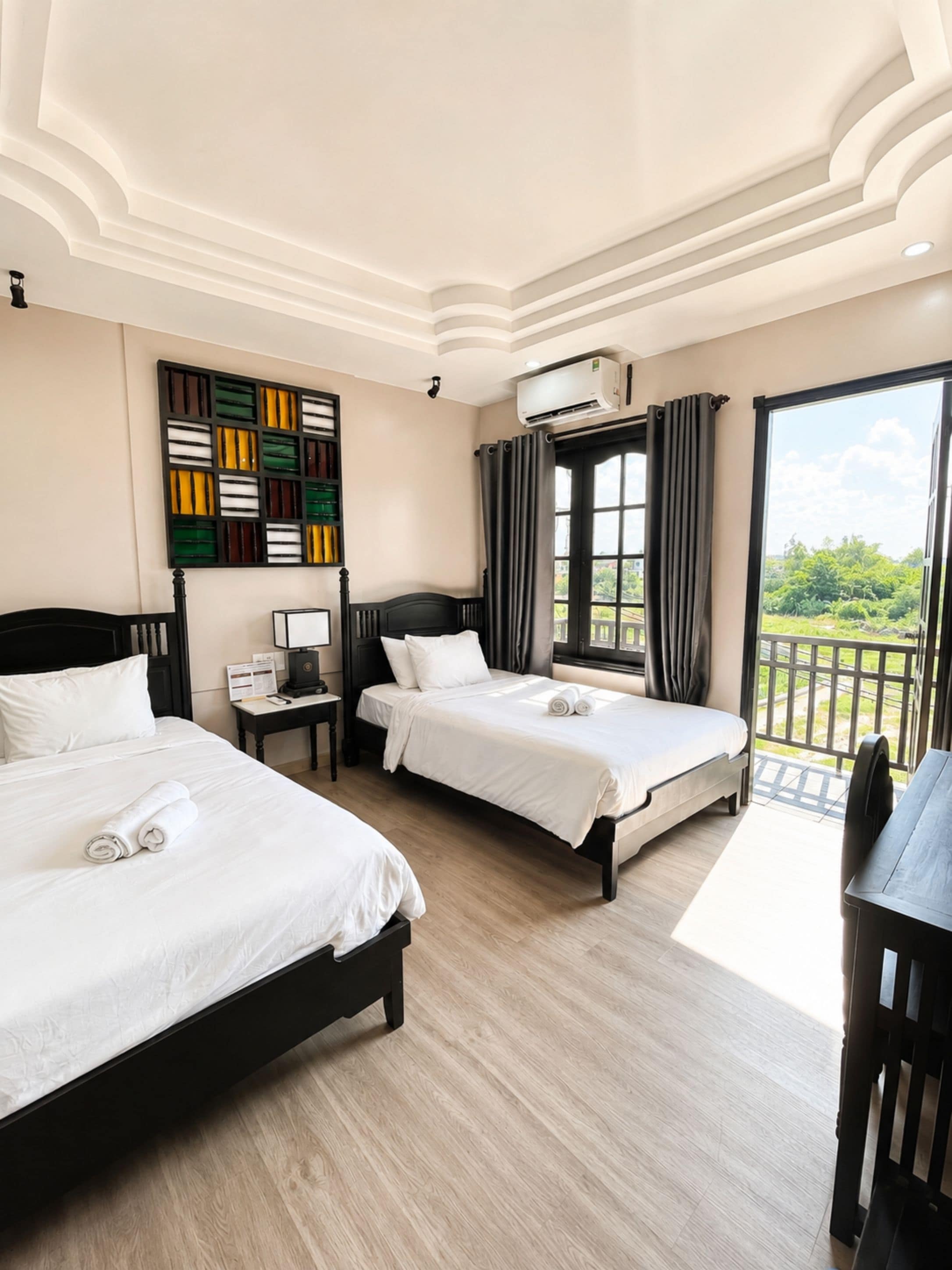 Habitación de hotel con dos camas, un escritorio, una ventana con cortinas y vistas a zonas verdes.