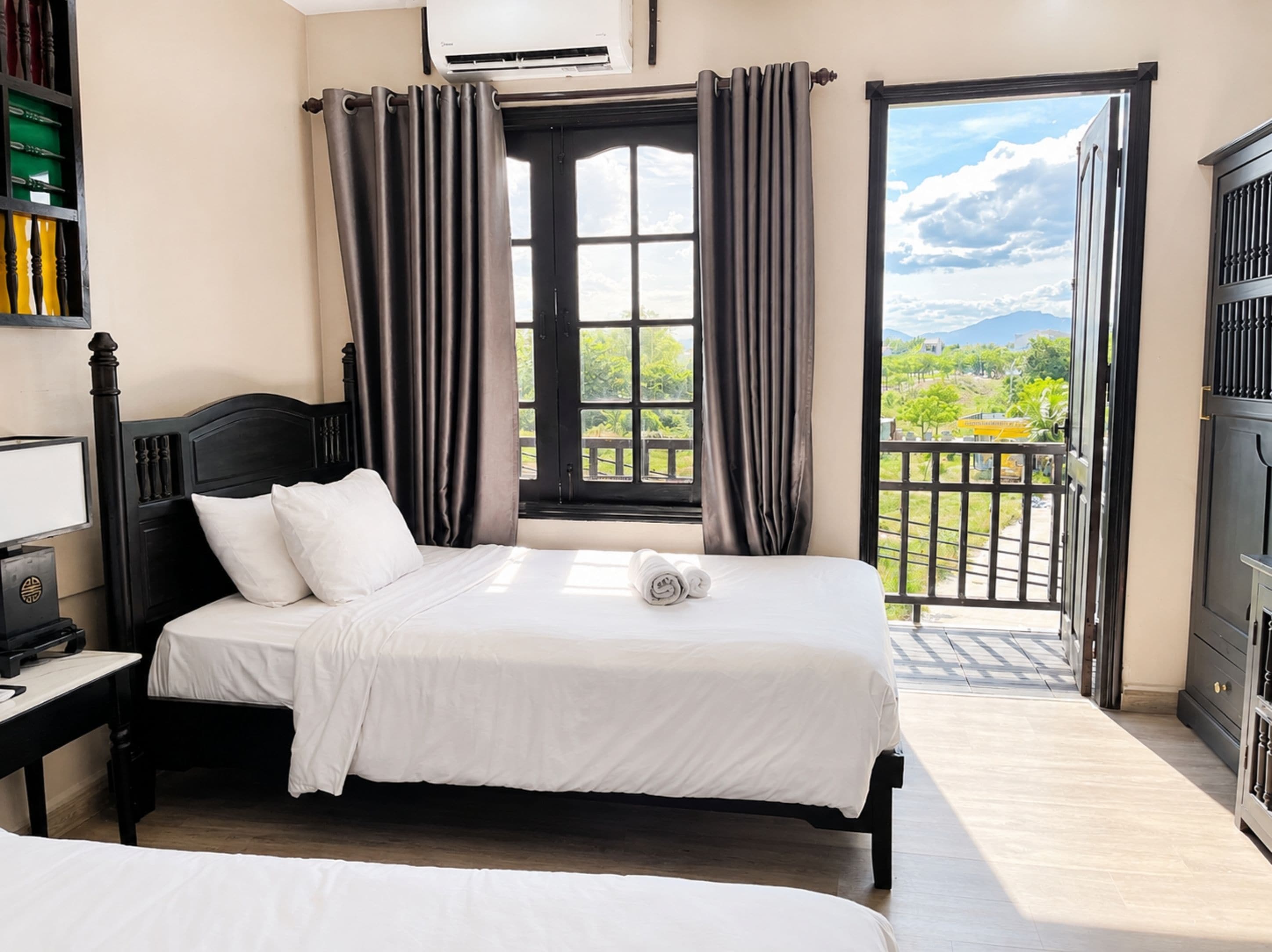 A bedroom with a bed, a nightstand, a bookshelf, and a view of a balcony with a railing.