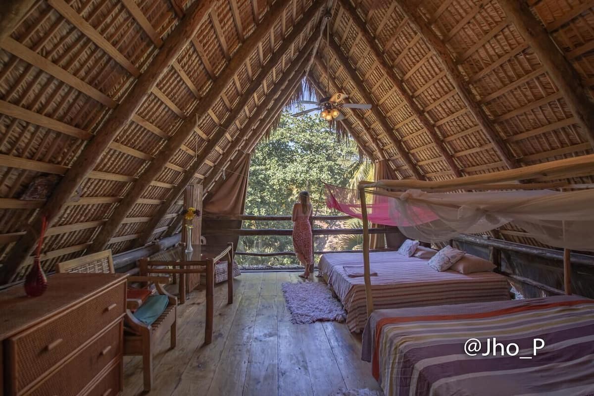 Una habitación acogedora con techo de paja, una cama, una silla y un escritorio.