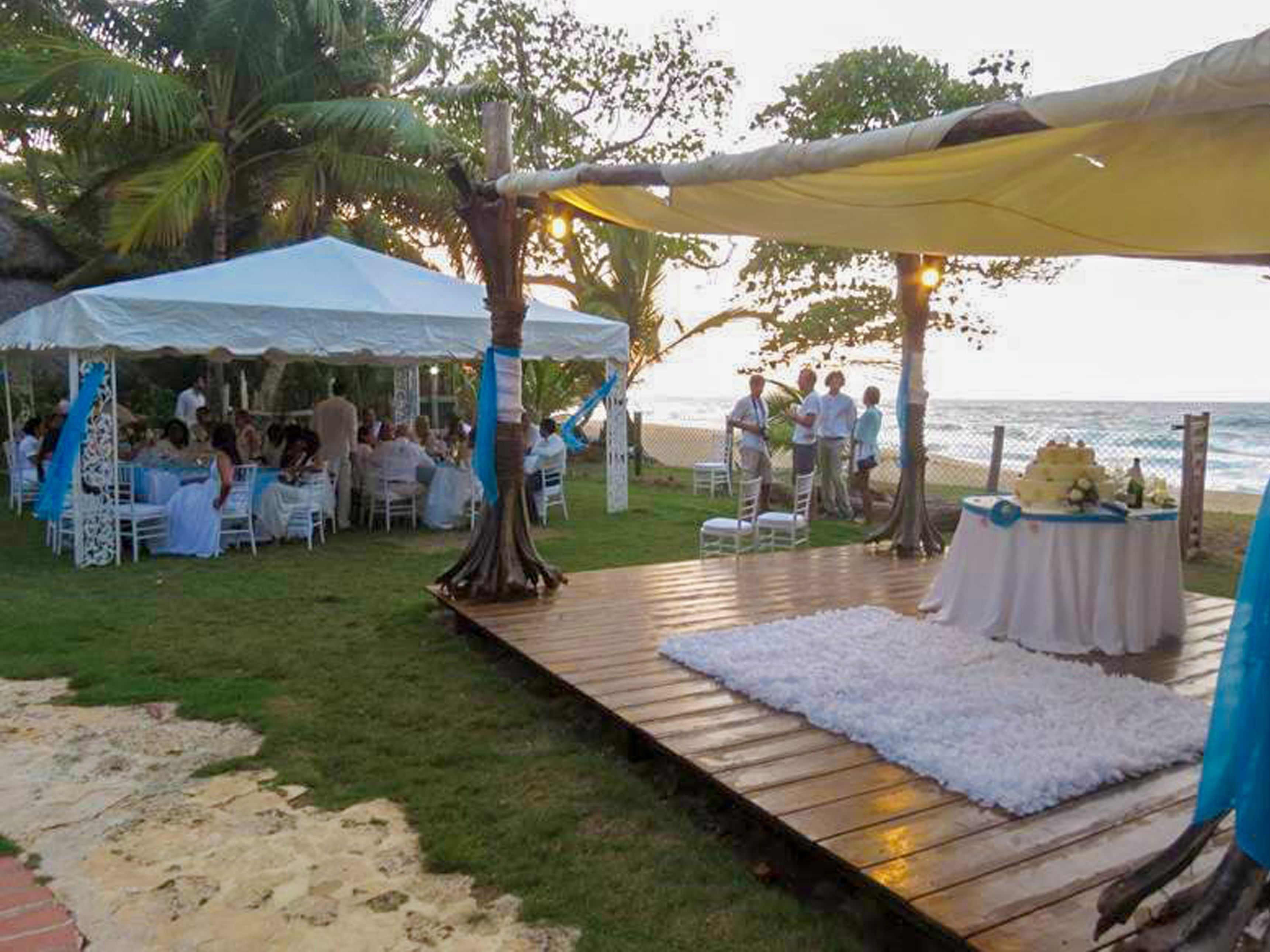 An outdoor event with a stage, white tents, and guests.
