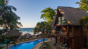A resort with a pool, lounge chairs, and a view of the ocean.