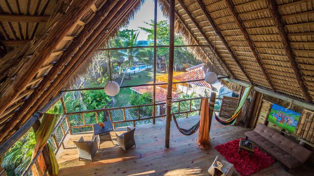 A wooden deck with a hammock, a sofa, and a dining table.