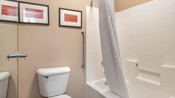 A bathroom with a toilet, a shower with a curtain, and two framed pictures on the wall.