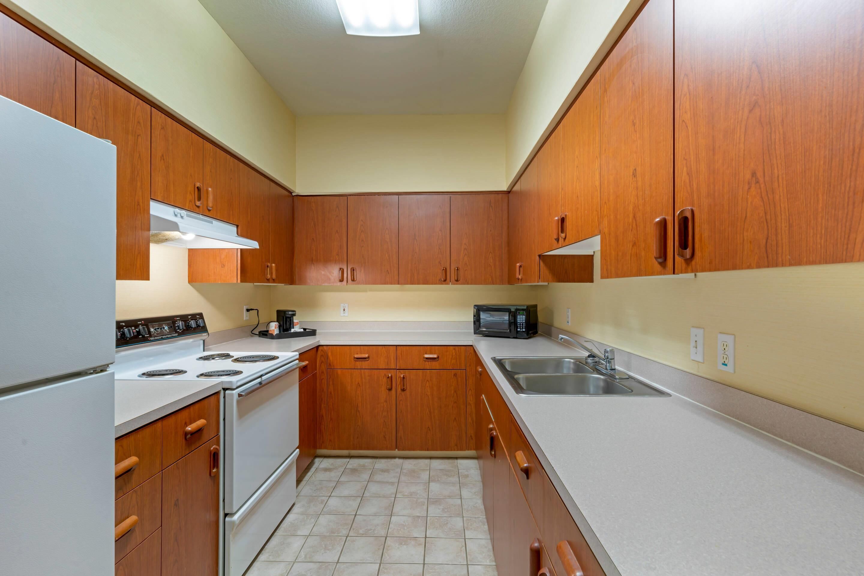 A kitchen with wooden cabinets, a stove, a microwave, and a sink.