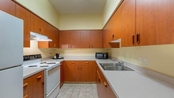 A kitchen with wooden cabinets, a stove, a microwave, and a sink.