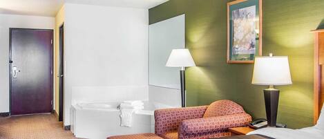 A hotel room with a bed, a sitting area with a sofa, a bathtub, two bedside lamps, and a painting on the wall.