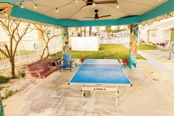 Une terrasse extérieure équipée d’une table de ping-pong, de sièges et d’un ventilateur de plafond.