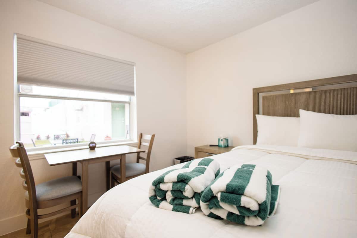 Une chambre d’hôtel avec un lit, un bureau et une chaise.