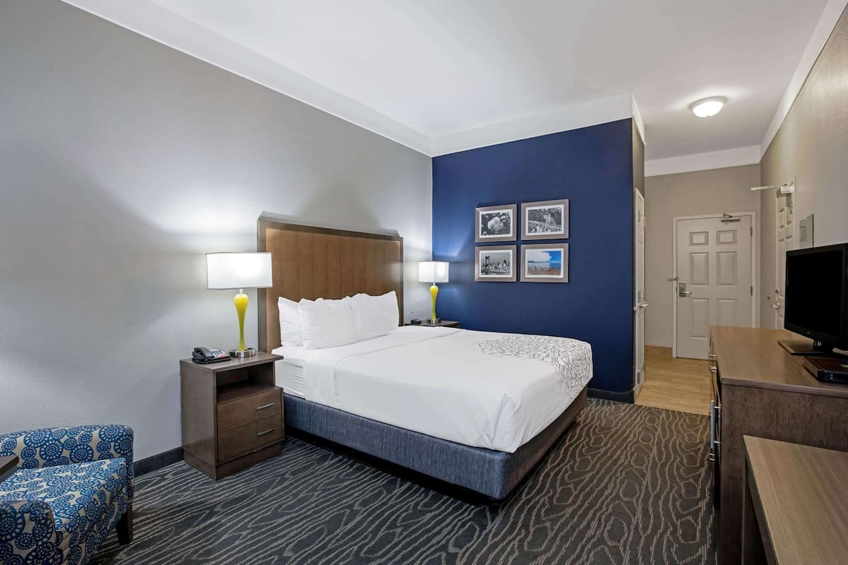 Une chambre d’hôtel comprenant un lit, des tables de chevet, un bureau, une chaise et un téléviseur.