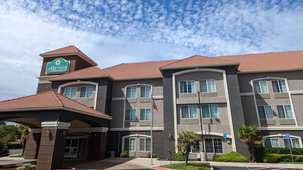 A hotel with a sign indicating 'La Quinta Inn Suites' and a flagpole with an American flag.