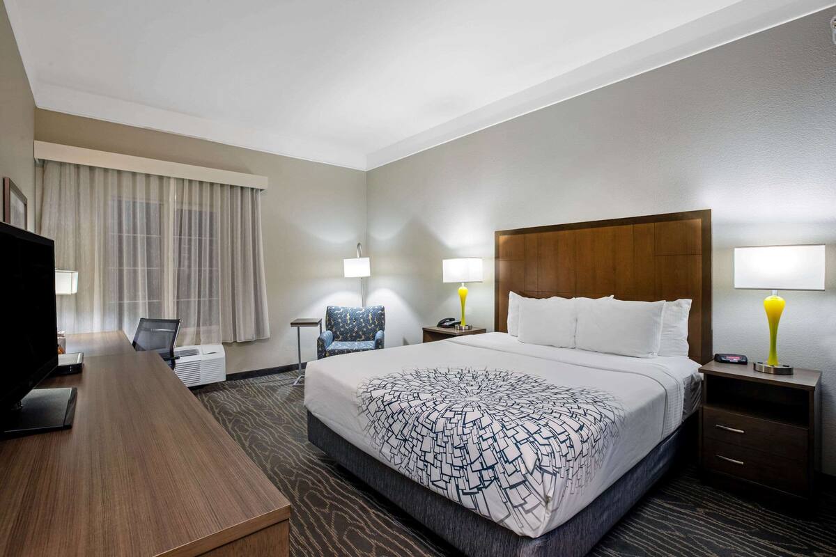 Une chambre d’hôtel avec un grand lit, un bureau, une chaise et un téléviseur.