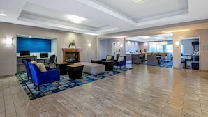 A spacious lobby with a modern design, featuring a seating area with sofas and armchairs, a reception desk, and a kitchen area in the background. - La Quinta Inn & Suites by Wyndham Manteca - Ripon (Ripon)