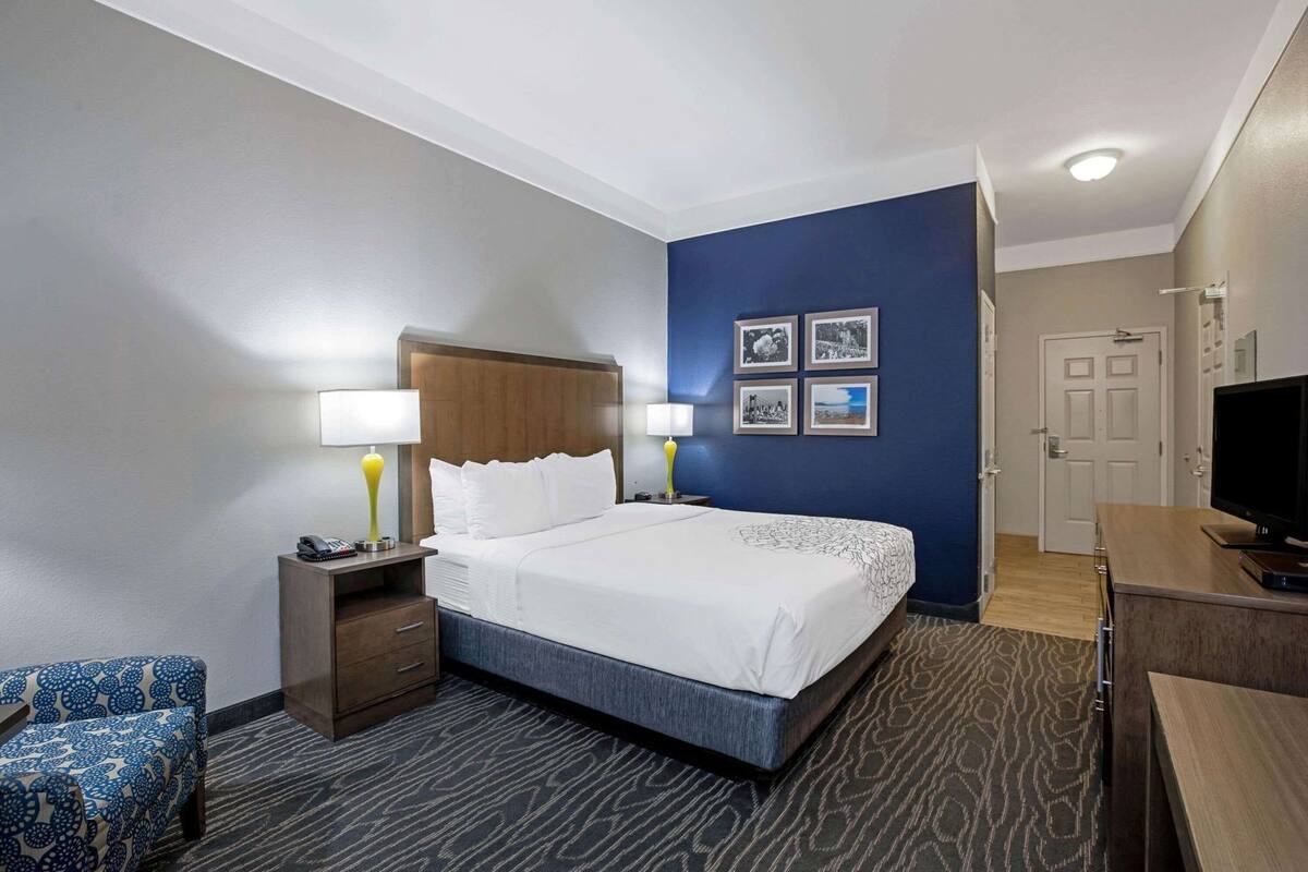 Une chambre d’hôtel comprenant un lit, des tables de chevet, un bureau, une télévision et une porte.
