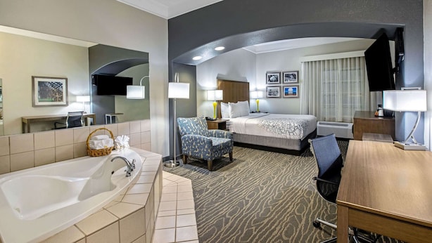 A hotel room with a large bathtub, a bed with a patterned bedspread, a desk with a chair, and a television. - La Quinta Inn & Suites by Wyndham Manteca - Ripon (Ripon)