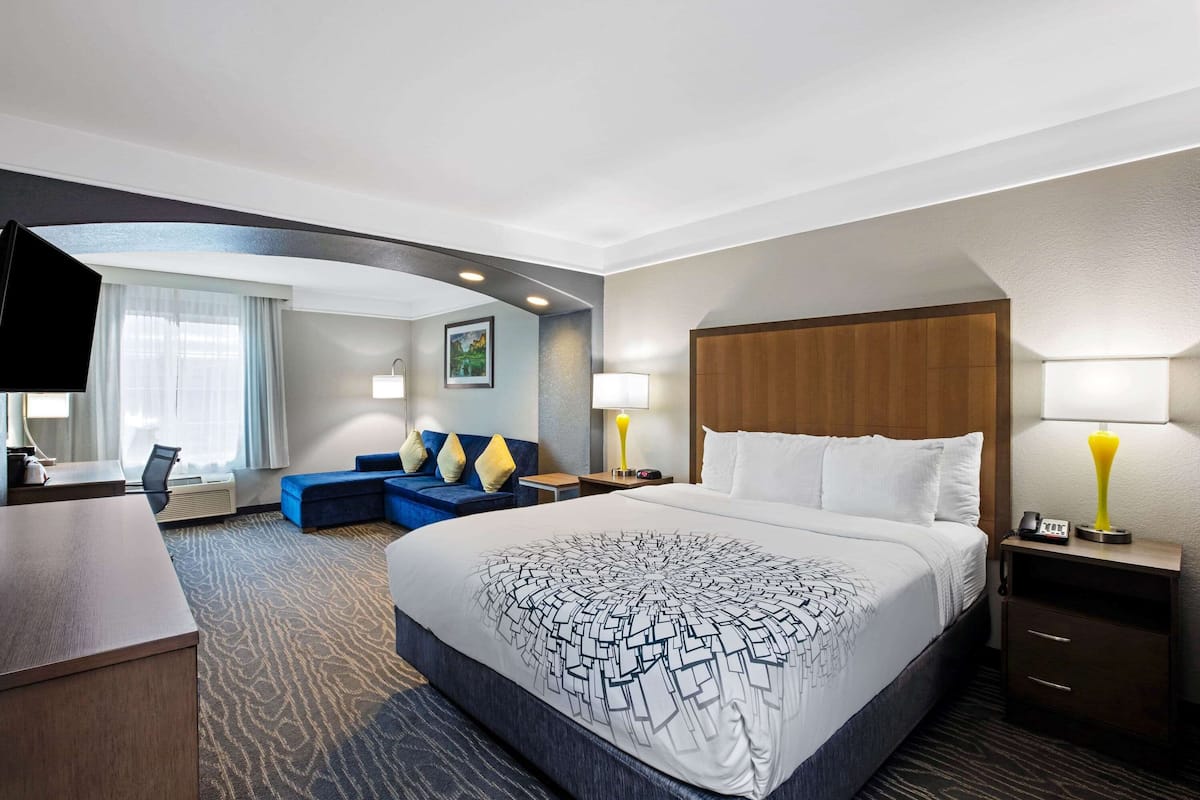 Une chambre d’hôtel avec un grand lit, un bureau, un canapé bleu et un téléviseur.
