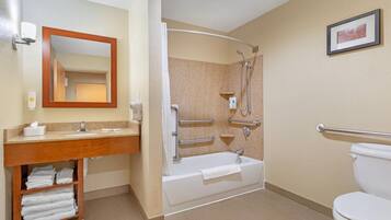 Une salle de bain comprenant un meuble-lavabo, un évier, un miroir, une douche et des toilettes.