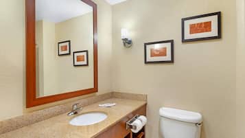 Une salle de bain avec un lavabo, un miroir, des toilettes et des tableaux encadrés accrochés au mur.